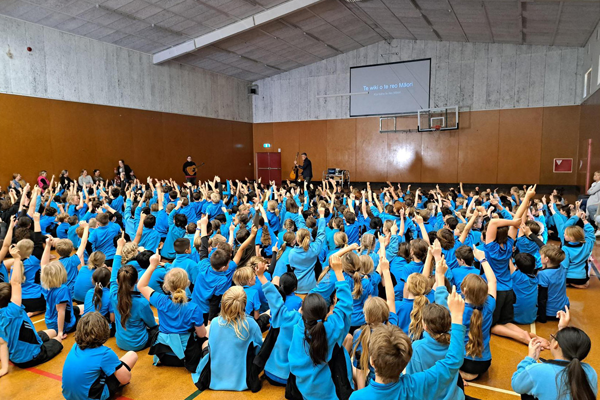 500 children sitting on a gym floor wearing blue uniforms.